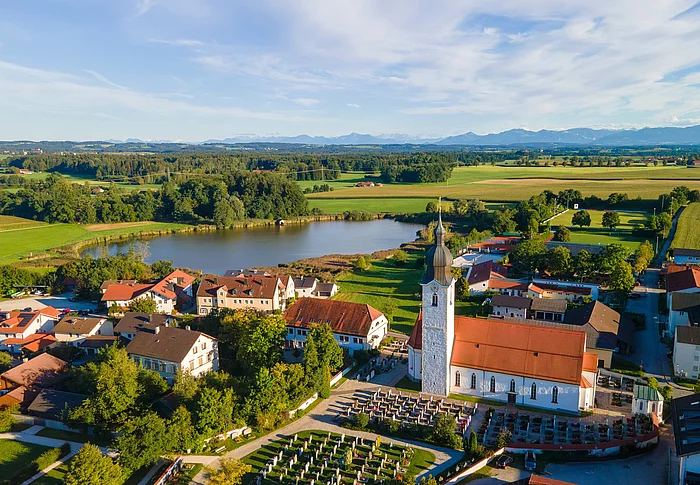 Das Foto zeigt eine Luftaufnahme von Eiselfing mit dem Eiselfinger See im Hintergrund.