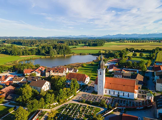 Das Foto zeigt eine Luftaufnahme von Eiselfing mit dem Eiselfinger See im Hintergrund.