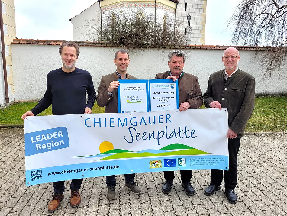 Das Foto zeigt die Übergabe eines Förderbescheids vor dem Rathaus in Eiselfing.
